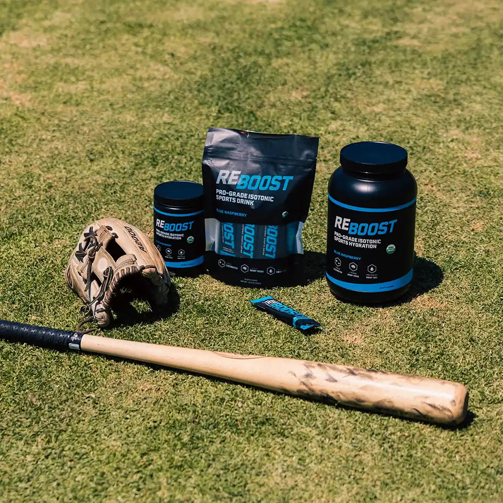 REBOOST hydration products on a grassy field with a baseball bat and glove.