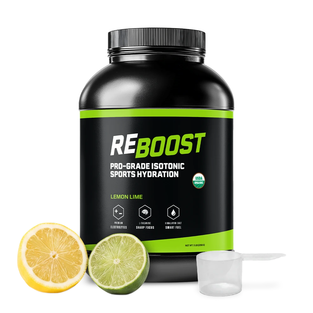 A black tub of REBOOST Pro-Grade Isotonic Sports Hydration in Lemon Lime flavor, shown on a white background with a sliced lemon, a sliced lime, and a clear scoop in front of the container.